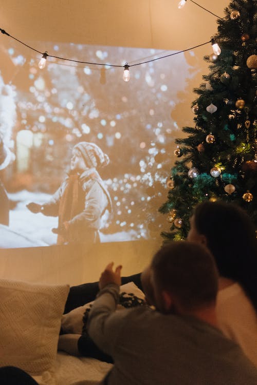 free-photo-of-a-couple-watching-a-movie-displayed-on-a-wall-from-a-projector-next-to-a-christmas-tree